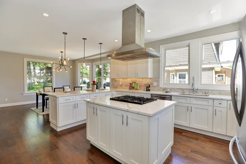 Warm hardwood in a kitchen with an island and a peninsula beneath a stainless range hood