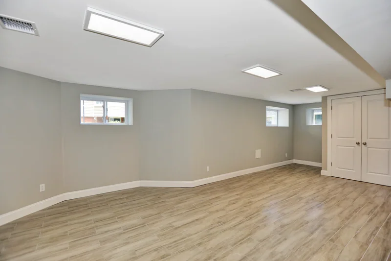 Wide light plank flooring in an empty finished lower level with high hopper windows
