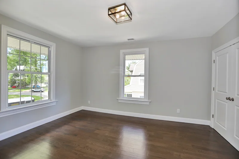 Dark hardwood in an empty corner room with two large windows