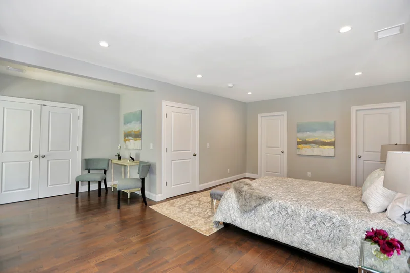 Warm hardwood in a staged bedroom with pale walls and a seating corner