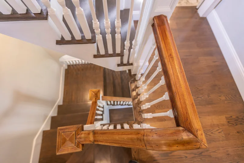 Looking down a stairwell past white turned balusters to square newel posts and dark treads