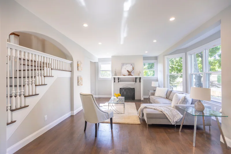 Warm hardwood in a staged living room with a fireplace and an arched stair opening