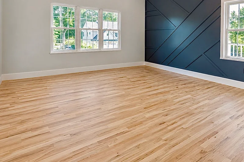 Pale hardwood running through an empty room with a navy batten accent wall between two windows