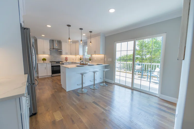 Warm hardwood in a white kitchen looking out to a deck through sliding doors