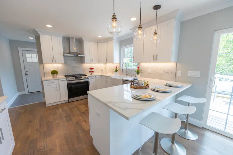 Warm hardwood in a white kitchen with a quartz counter and a stainless range hood