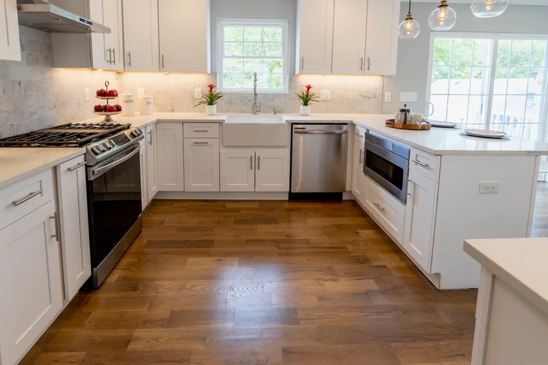 Warm hardwood in a white kitchen with an apron-front sink and a built-in drawer microwave