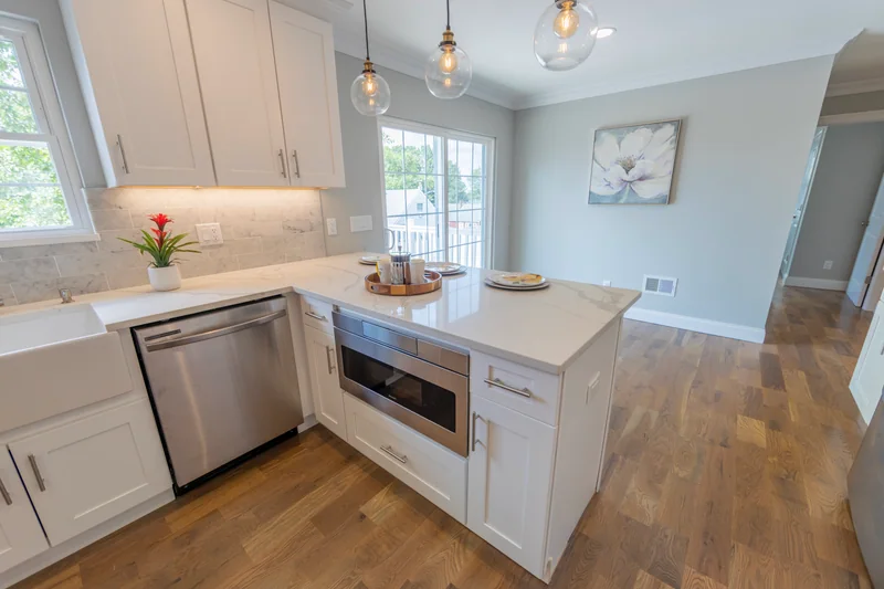 Warm hardwood in a kitchen with a quartz peninsula and a built-in drawer microwave