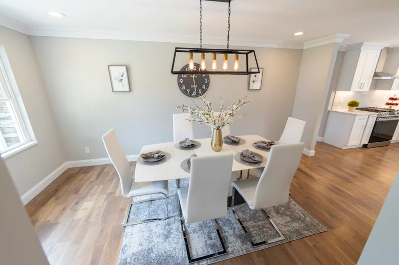 Warm hardwood in a dining area under a black and brass linear chandelier