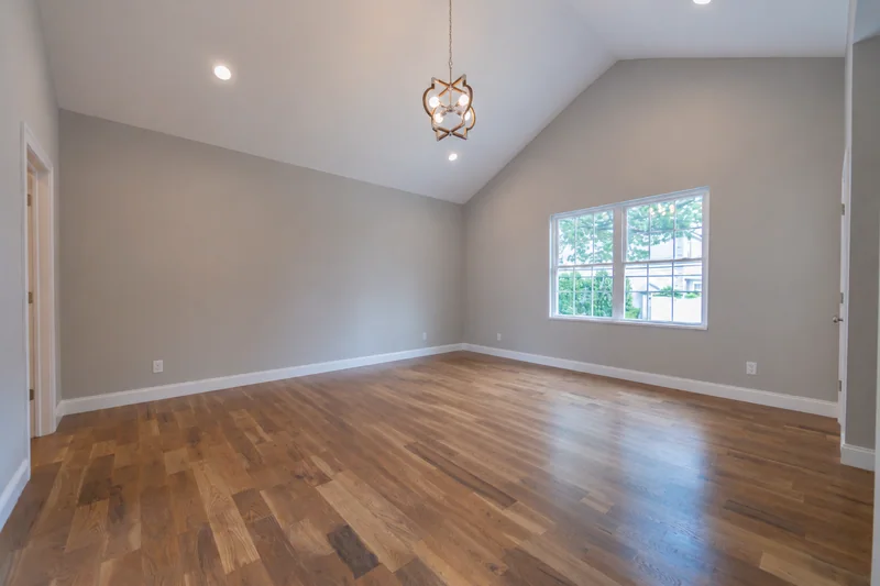 Warm hardwood in an empty vaulted room with a single window
