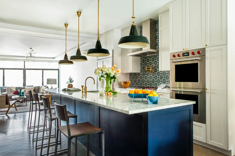 Wood floor in a kitchen with a navy island, brass fittings and a patterned green tile backsplash