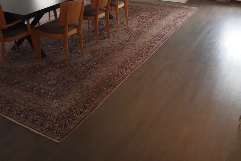 Dark wide-plank flooring in a loft dining area against an exposed brick wall