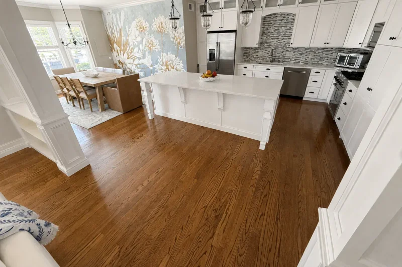 Elevated view of refinished red oak flooring spanning the kitchen, island and dining area of a Point Pleasant NJ home