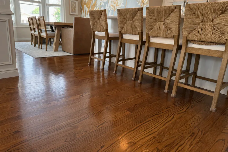 Refinished red oak floor viewed past woven counter stools toward the dining room in a Point Pleasant NJ home