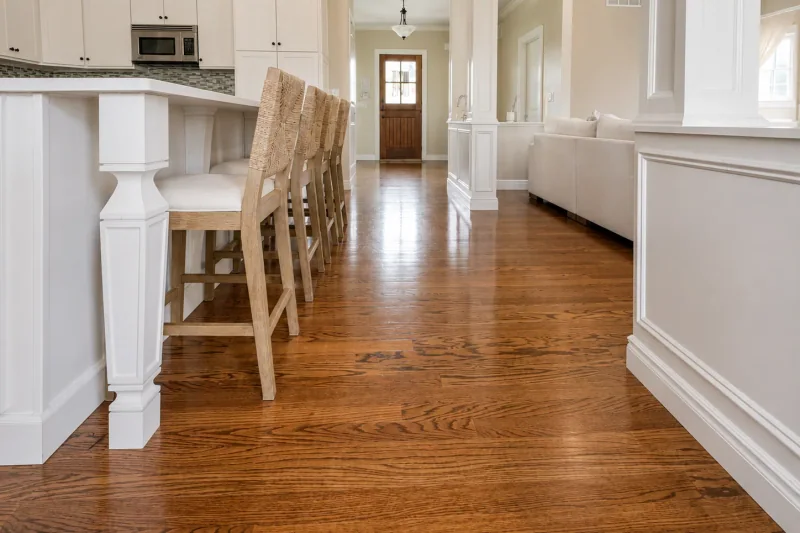Refinished red oak flooring stretching from the kitchen island to the wood front door of a Point Pleasant NJ home