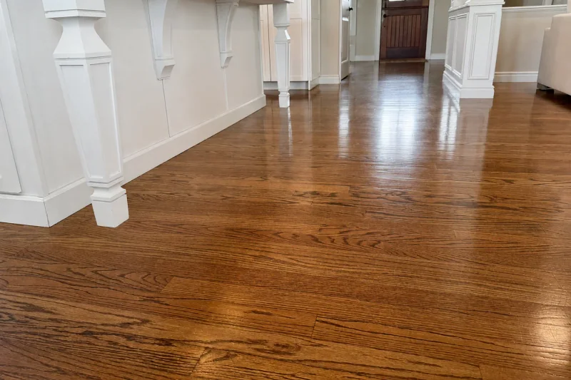 Glossy refinished red oak flooring running alongside a white kitchen island toward the front entry of a Point Pleasant NJ home