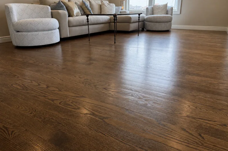 Living room with wide refinished red oak flooring, a cream sectional sofa and swivel chairs
