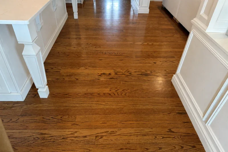 Close view of red oak plank grain and warm stain beside a white quartz-topped kitchen island
