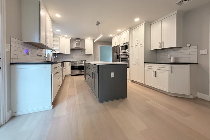 Pale wide-plank hardwood in a finished white kitchen with a grey island
