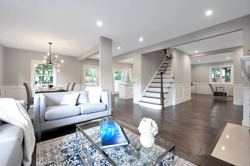 Dark hardwood in a staged living room beside an open staircase