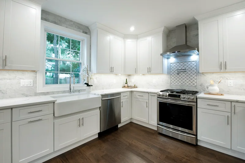 Dark hardwood in a white kitchen with a farmhouse sink and a stainless range hood