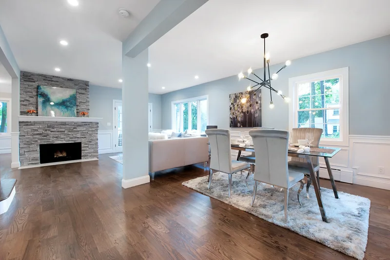Dark hardwood in an open dining area beside a stone fireplace