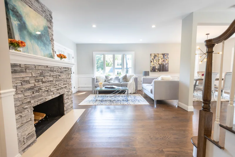 Dark hardwood flowing past a floor-to-ceiling stone fireplace into an open living room