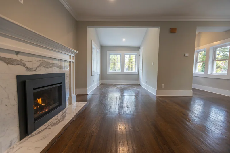 Dark hardwood running past a marble fireplace toward a window alcove