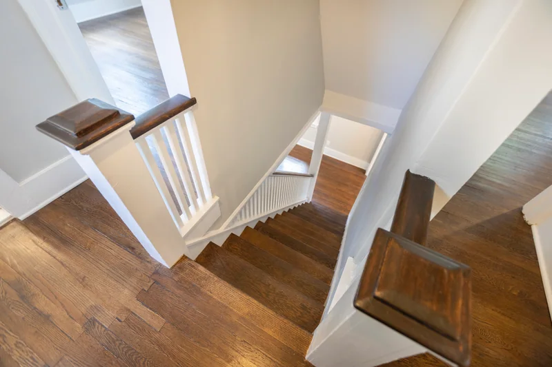 Looking down a white staircase onto dark hardwood treads and a landing