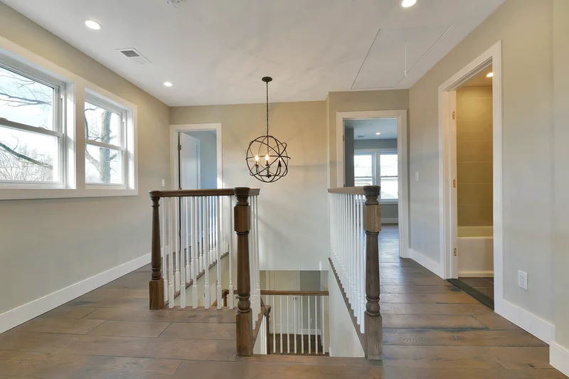 Wide grey-toned hardwood on an upper landing with a turned newel post and open stairwell