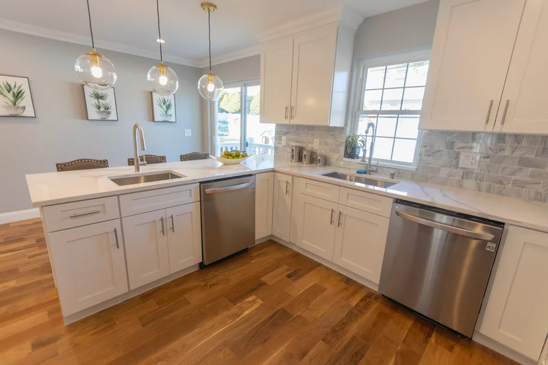 Golden hardwood in a white kitchen with a peninsula and a stainless dishwasher