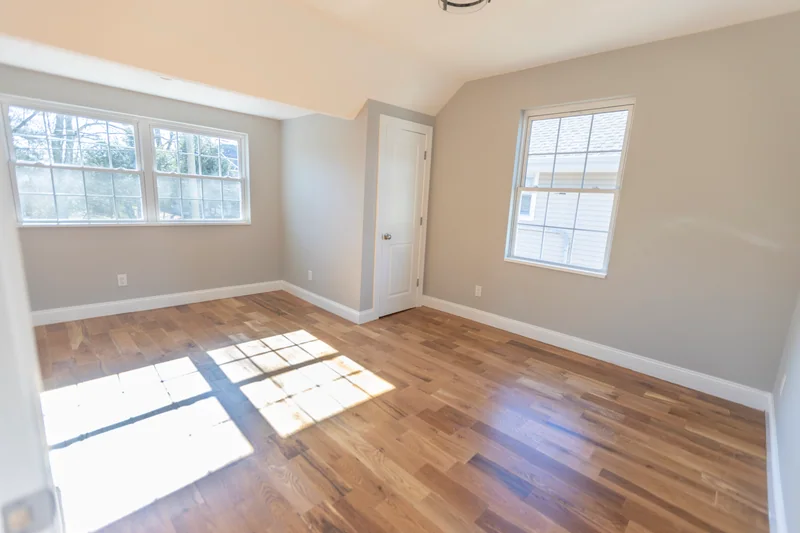 Sunlight across golden-brown hardwood in an empty upstairs room with a sloped ceiling