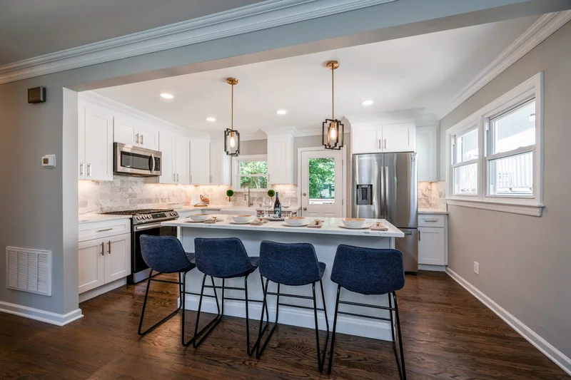 Dark hardwood in a white kitchen with an island and four navy counter stools
