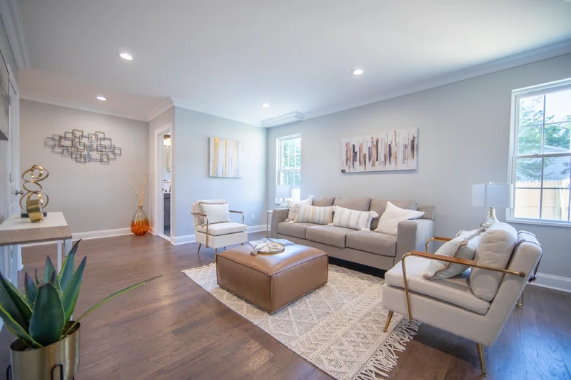 Medium-brown hardwood in a staged living room with a leather ottoman and a woven rug
