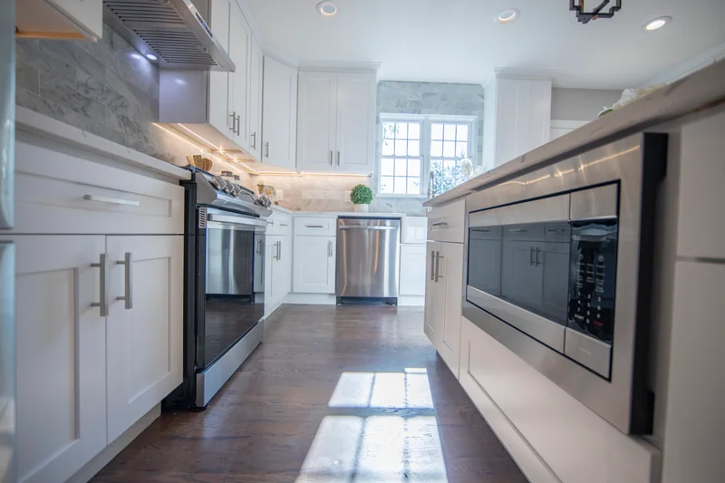 Medium-brown hardwood in a white kitchen, seen past a microwave built into the island