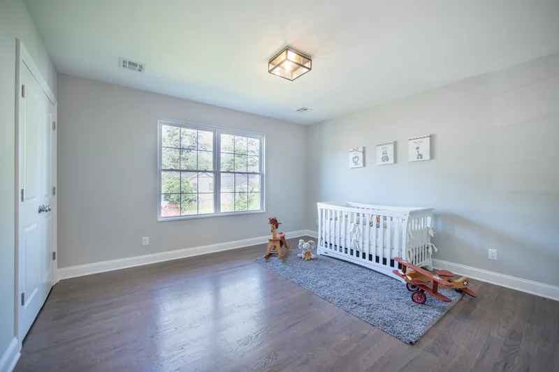Medium-brown hardwood in a nursery with a white crib and a grey rug