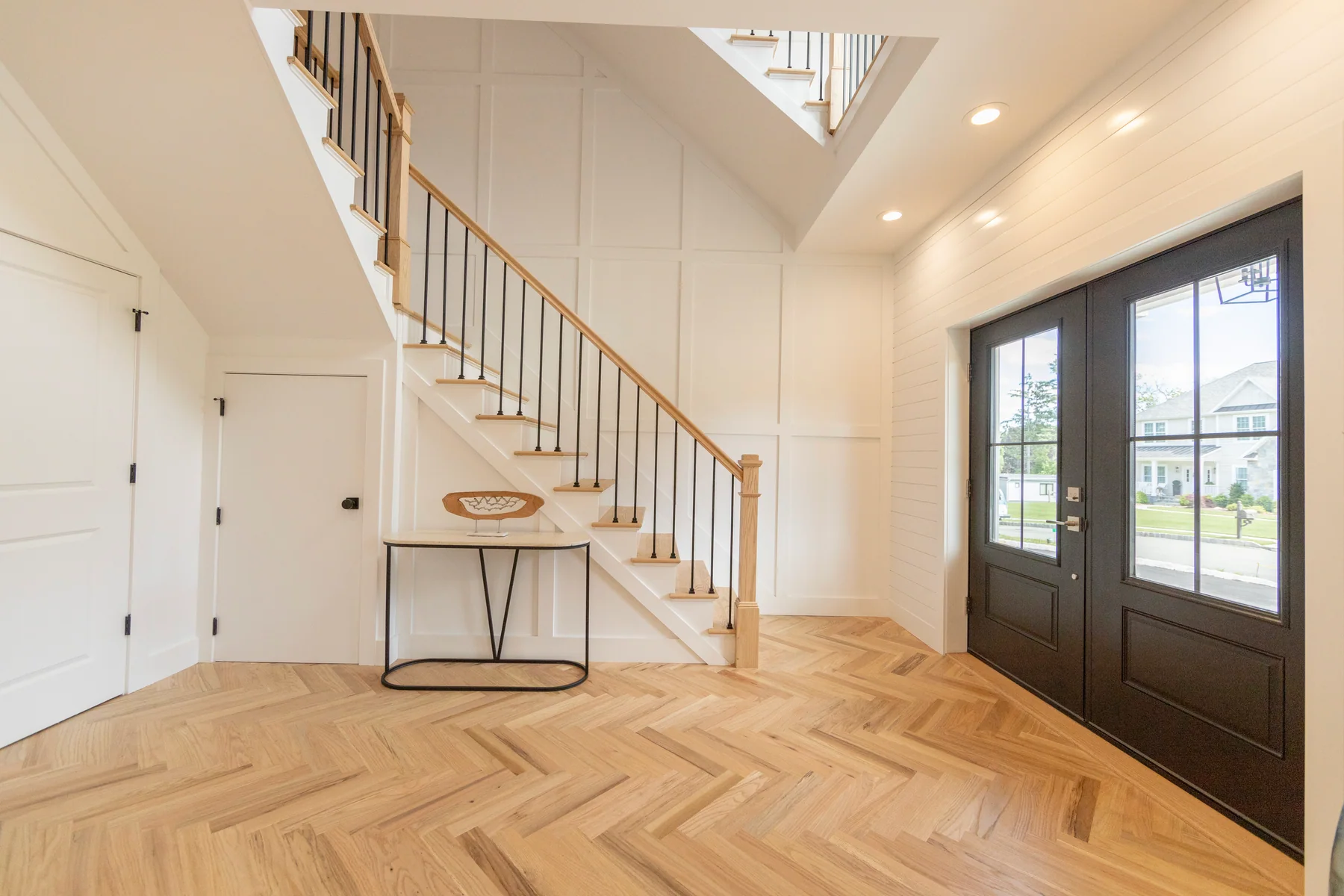 Light oak laid in a herringbone pattern across a bright entry hall
