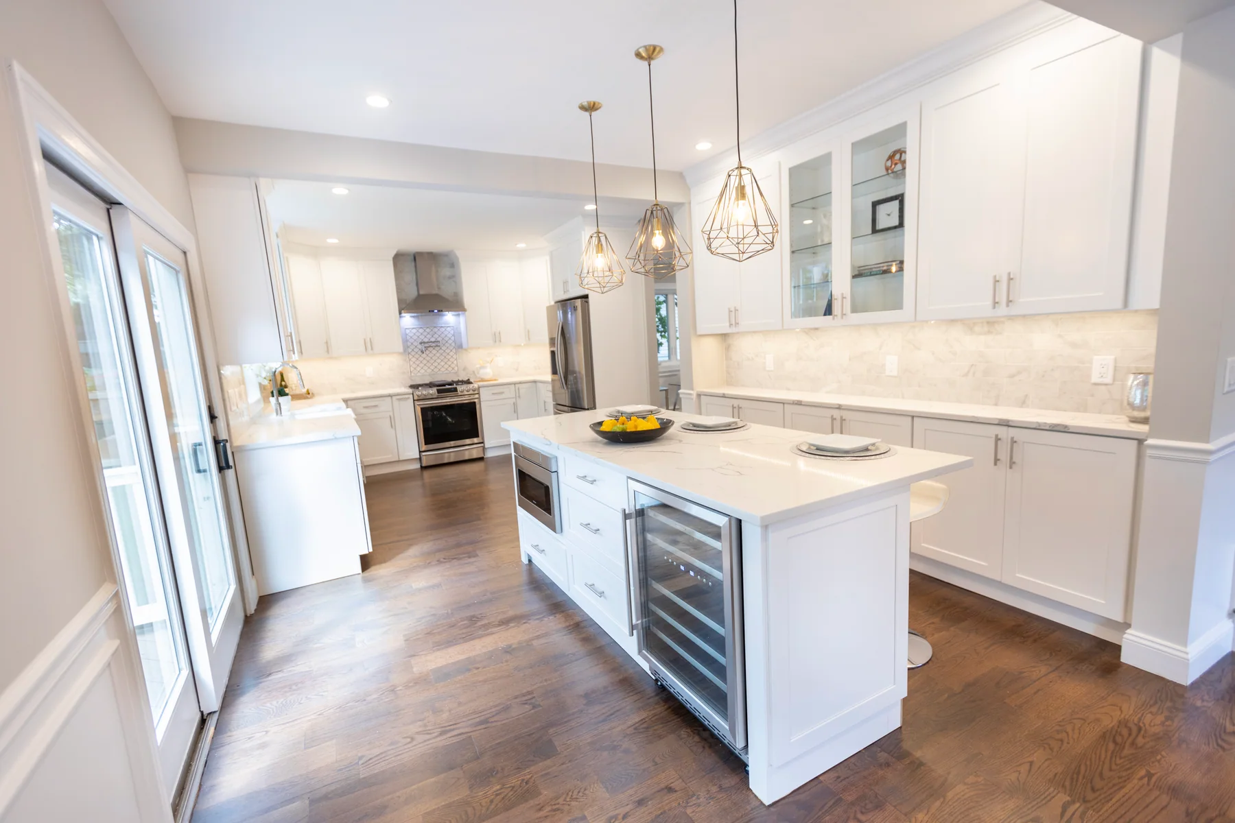Dark hardwood in a white kitchen with a marble island and pendant lighting
