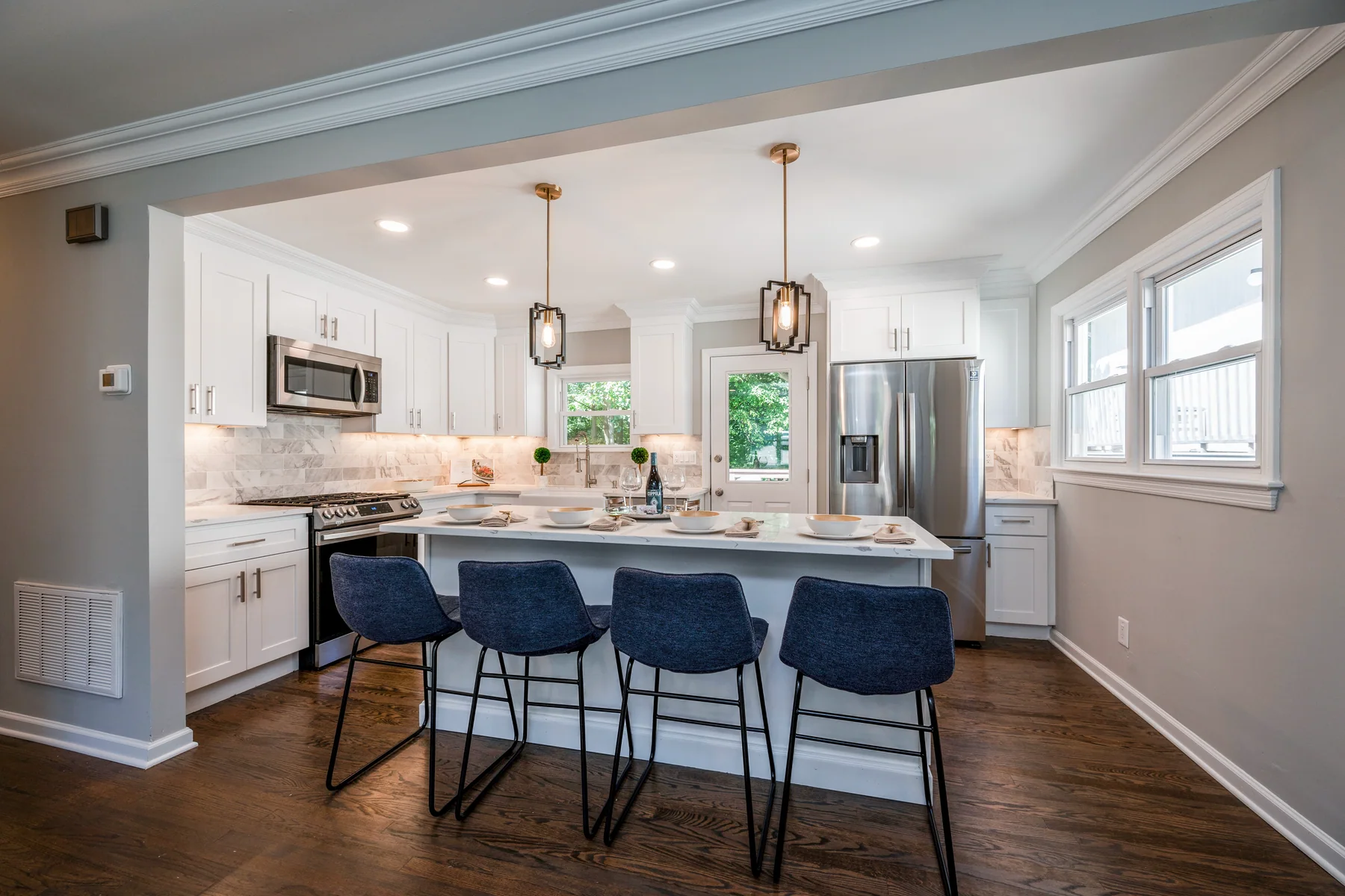 Dark hardwood in a white kitchen with an island and navy counter stools