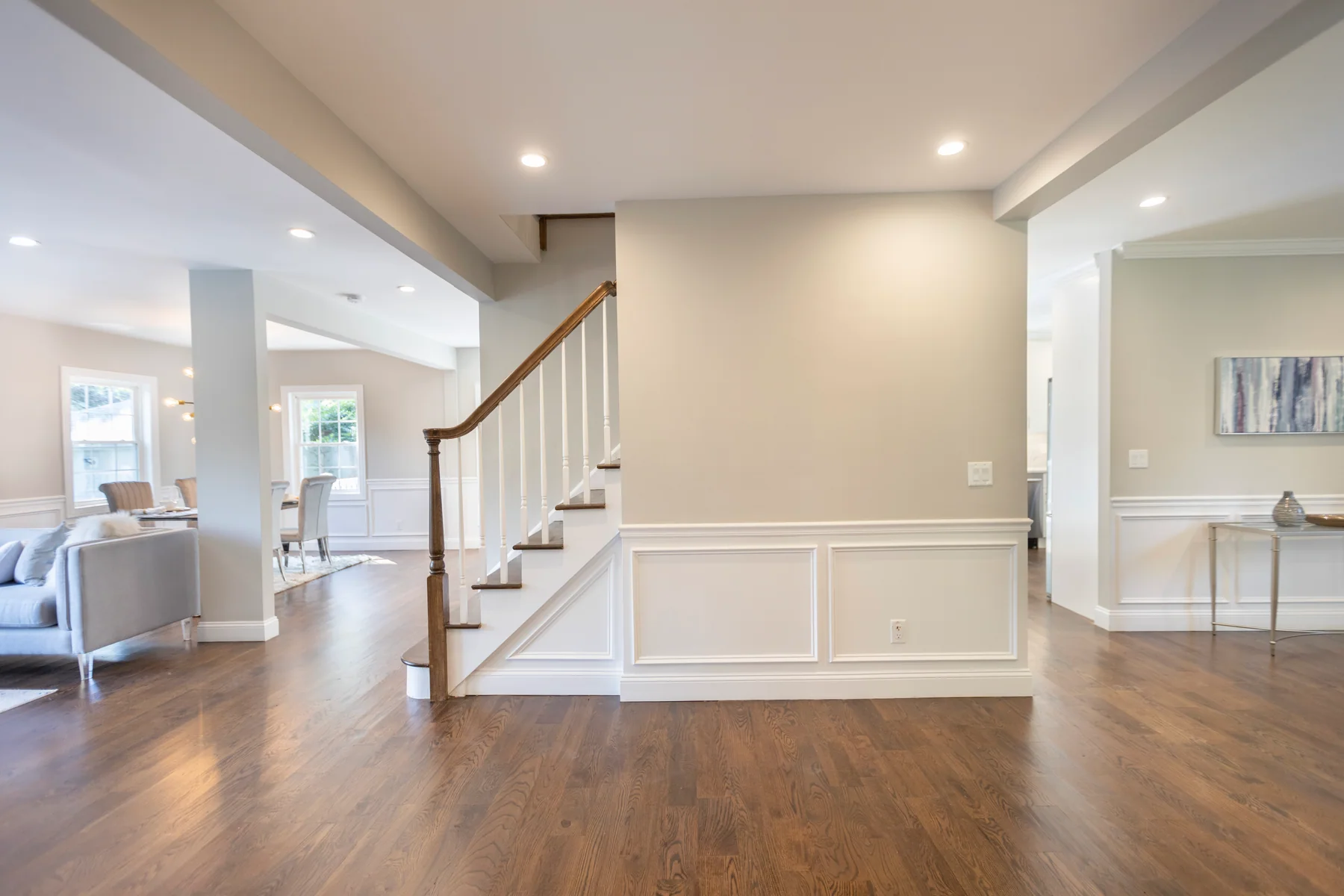 Dark hardwood in an open living space at the foot of a white staircase